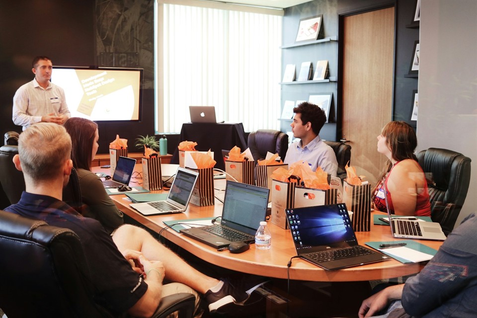 Two professionals shaking hands over a desk during a business meeting