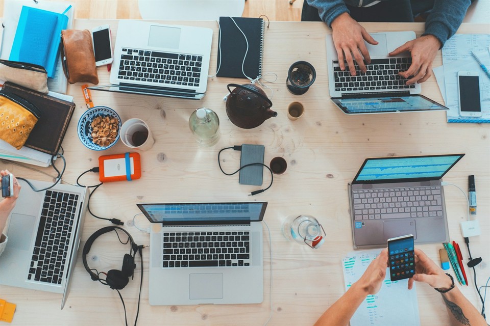 Team of professionals collaborating around a table with laptops